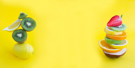 Pyramid of chopped fruit in balance on the yellow background. Banner. Copy space.