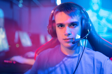 Portrait popular young caucasian man pro gamer streamer playing in online video game, neon color...