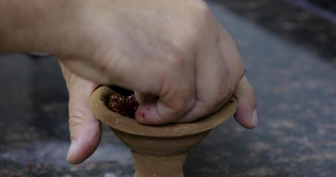 Someone is making head of shish and adjusting tobacco on it