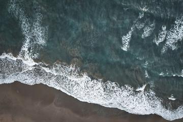 Obraz na płótnie Canvas Big waves crushing on a sandy beach - blue green ocean captured with a drone - Canggu Bali