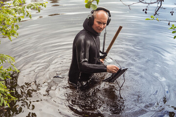 a man with a water metal detector in the water looking for gold
