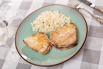 Tasty baked tuna steak served on black plate with white rice. Healthy dinner concept
