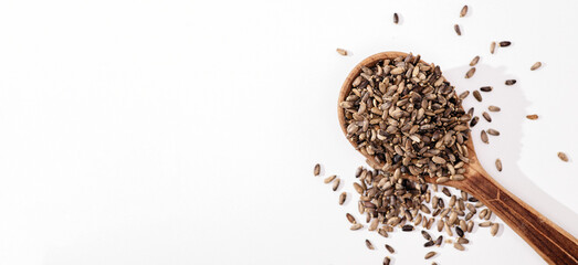 Thistle seeds in a wooden spoon on a white background, place for text, top view,baner