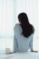 woman doing sitting on bed after wake up with coffee mug