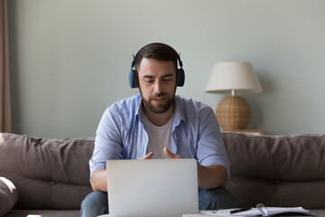 Confident engaged freelancer business man in big headphones speaking on video call on laptop, negotiating to client. Student, teacher, blogger man giving online workshop, learning webinar, lesson
