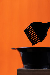 Hairdresser tools for dyeing hair. Applicator brush and tint mixing bowl on orange background - 531386914