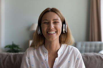 Cheerful happy pretty Caucasian woman wearing wireless headset head shot portrait. Millennial...