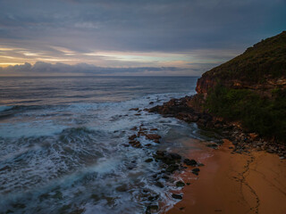 Cloud covered sunrise at the seaside in pink and blue