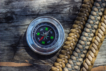 paracord bracelets and navigational compass on wooden board