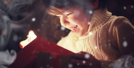 Family on Christmas eve at fireplace. Kids opening Xmas presents. Children under Christmas tree with gift boxes. Decorated living room with traditional fire place. Cozy warm winter evening at home.