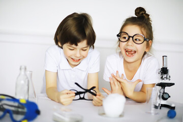 Two cute children at chemistry lesson making experiments on white background