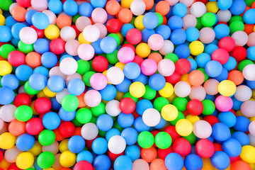 Fototapeta na wymiar Multi-colored, highly saturated plastic balls, in soft play ball pit, at a child's play park. Colorful balloon.