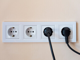 Two electrical power plugs for household appliances are connected to the electrical network. Unplug half of the electrical appliances from the outlet.