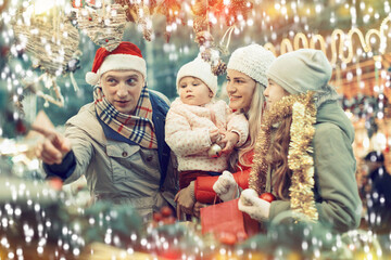 Portrait of cheerful man and woman with their happy daughters near counter buying Christmas decorations
