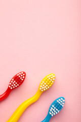 Colorful toothbrushes on pink background. Top view