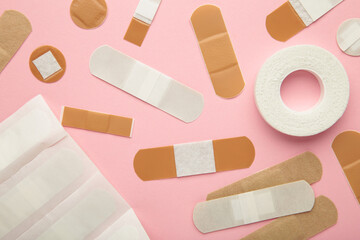 Beige adhesive bandages on pink background. Medical plasters