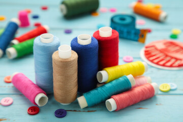Sewing supplies on blue background: sewing thread, scissors, a large spool of thread, pieces of...