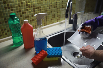 A bottle with an environmentally friendly dishwashing detergent on the background of a housewife washing dishes