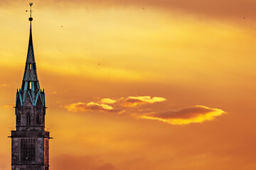 Church tower in Nuremberg in front of orange sunset over the city in Germany. 