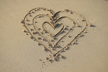 Family of hearts drawn on the sand of the beach