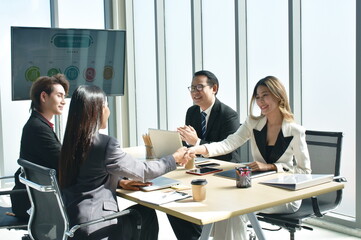 Asian business women shaking hand together after meeting with success and win deal in office room