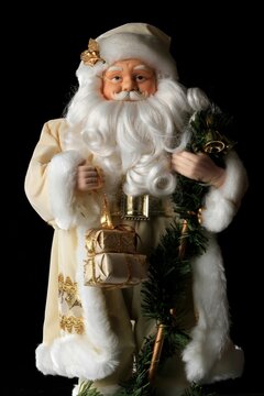 Santa Claus Christmas Figurine In White Suit Isolated On A Black Background