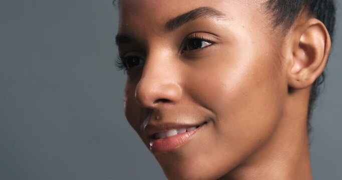 Model smile with rainbow light on face against grey studio background or wall. Black woman in beauty or skincare has iridescent neon lighting shine on skin in wellness or cosmetic portrait.