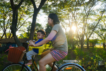 Obraz premium Little boy sitting on bike chair ride bicycle with mother in park sunset