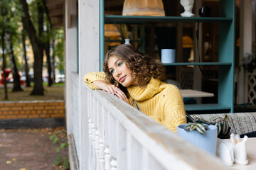 Young woman sitting in coffee or cafeteria and posing