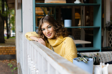 Young woman sitting in coffee or cafeteria and posing