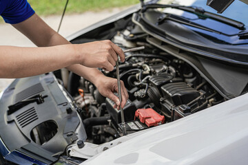 A young man checks the oil level and repairs the car before leaving.