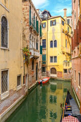 Fototapeta na wymiar View on the narrow cozy streets of the canals with parked boats in Venice, Italy. Architecture and landmark of Venice.