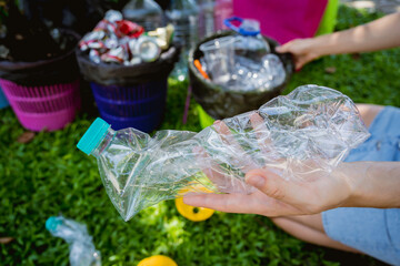 Young beautiful girl sorts garbage into special bins