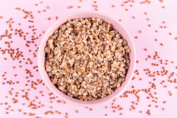 Buckwheat porridge in a bowl (plate) on a pink background close-up. Porridge for a child (baby). Healthy breakfast, side dish.