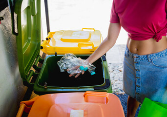 A young beautiful girl throws sorted garbage into special bins