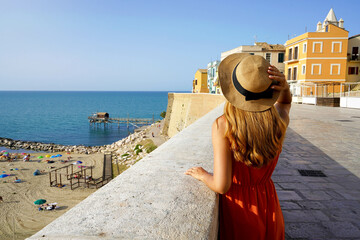 Summer holiday in Italy. Back view of young traveler woman visiting the old town of Termoli, Molise, Italy. - obrazy, fototapety, plakaty