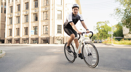 A male cyclist in a helmet rides a bicycle, training in the city.