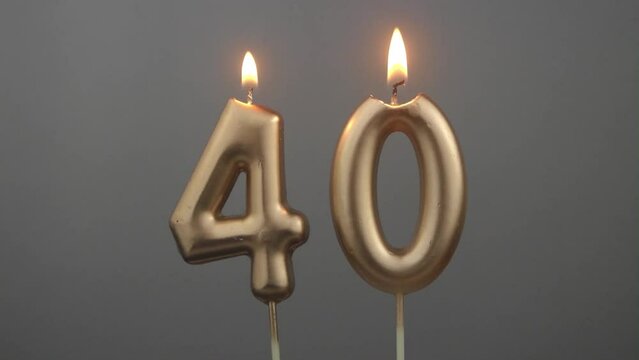 Burning gold birthday candles on gray background, number 40
