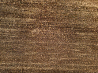 Agriculture concept. Aerial drone view of brown dirt rural agricultural field background in high altitude. Harvested crops with visible stubble. Earth view from above. Image contain noise and blur