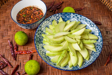 Green mango with sweet fish sauce on the wooden background.