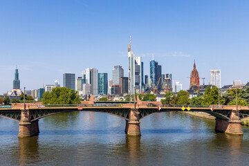 Frankfurt skyline and Ignatz Bubis bridge at daytime with the Main river in the foreground, taken from the Flösserbrücke bridge