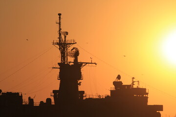 Sunset over the silhouette army ship