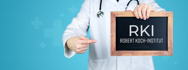 RKI (Robert Koch-Institut). Arzt zeigt medizinischen Begriff auf einem Schild/einer Tafel