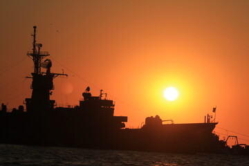 Sunset over the silhouette army ship