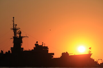 Sunset over the silhouette army ship