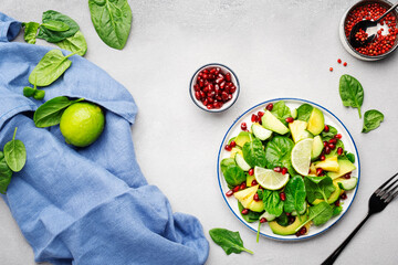 Fresh vegan salad with pineapple, spinach, avocado and pomegranate seeds, gray kitchen table, top view. Healthy eating, clean food, diet, weight loss concept