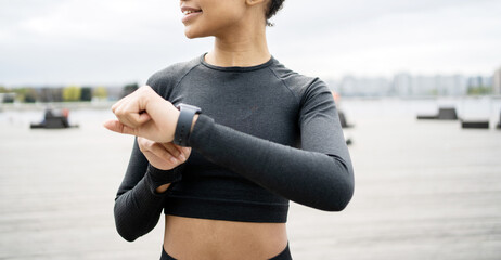 A fitness watch and a running app are on hand. An athlete in a tight tracksuit trains outside.