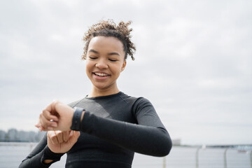 Fitness watch and sports app. A young woman smiling runner is training fitness running in the city.