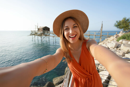 Sunset girl takes selfie photo with trabucco old fishing machine on the background