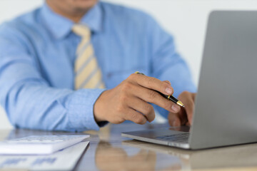 Fototapeta premium Businessman working on laptop checking accounts and analyzing charts in financial documents. Financial planning and accounting.